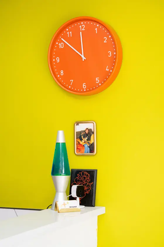 Orange clock and lava lamp against the chartreuse wall