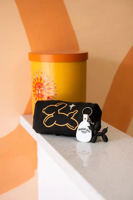 Black Dog merch: an orange canister, a logo pouch, and a keychain