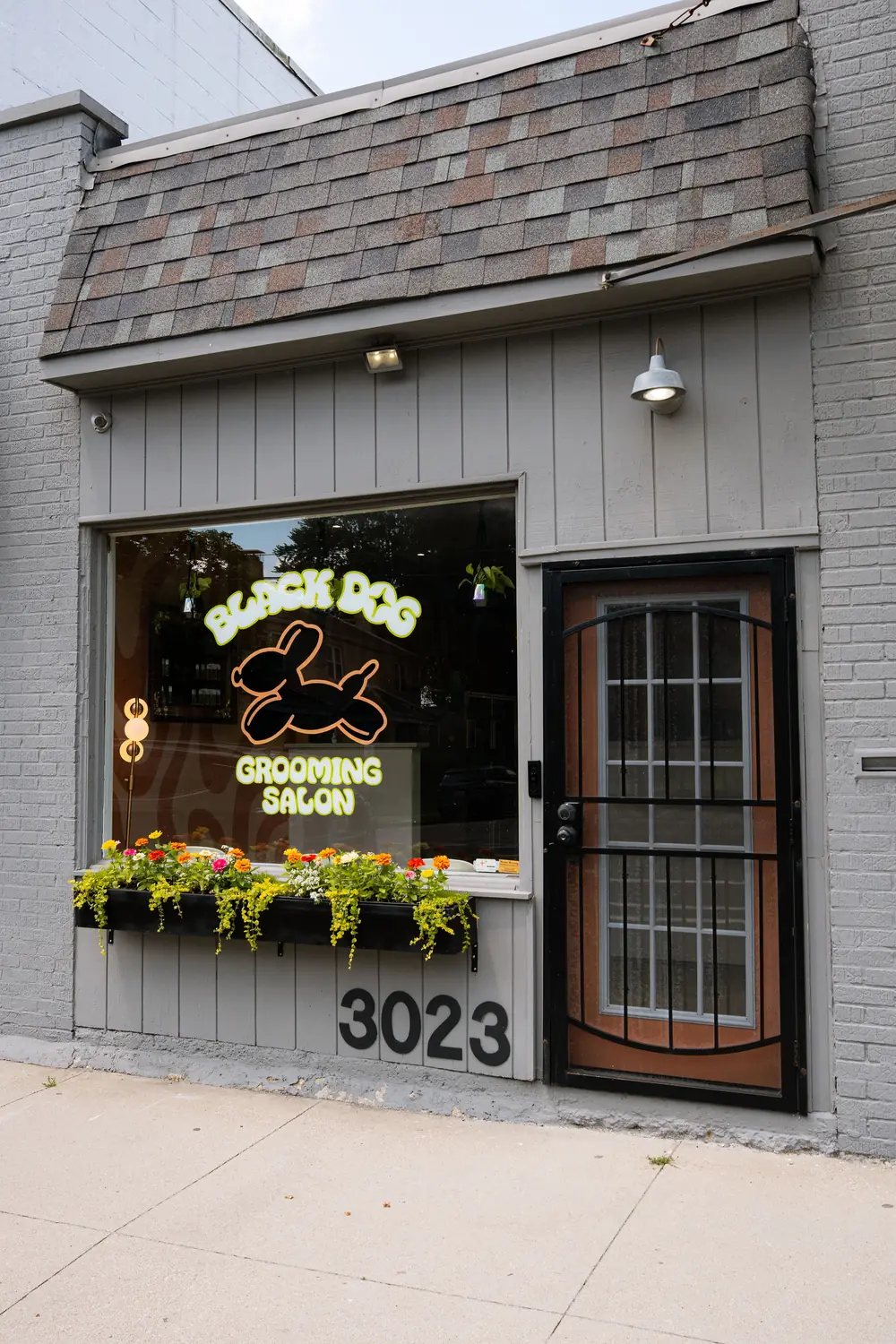 Black Dog Grooming Salon storefront at 3023 Indianola Ave with the balloon-dog logo in the window and a flower box